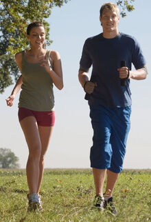 Mann und Frau joggen nebeneinander über ein Feld
